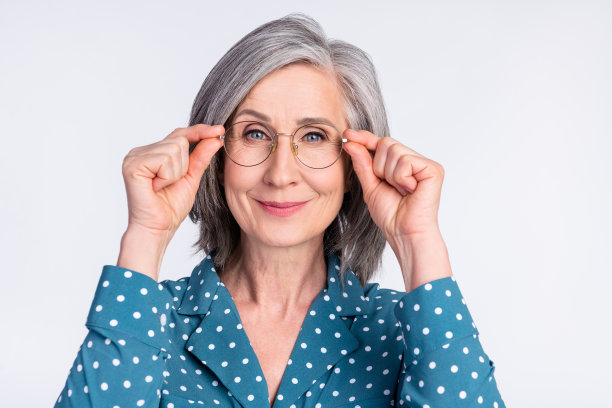 穿着点点衬衫、戴着眼镜的年长女商人的照片肖像，背景为白色。图片下载