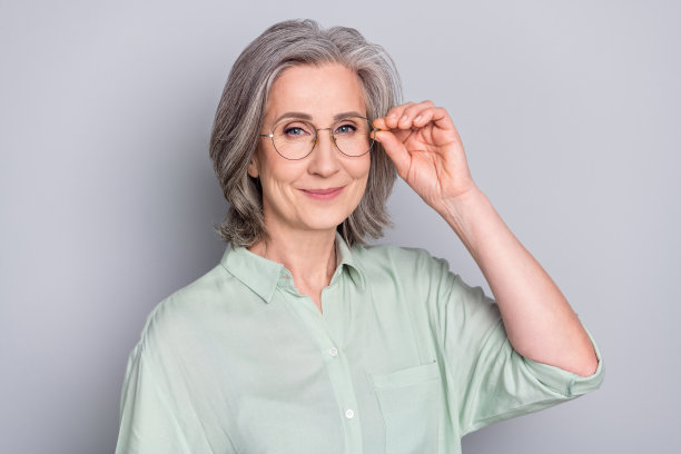 快乐、积极、微笑的美丽、可爱、聪明的女商人在灰色背景下戴着眼镜的照片图片下载