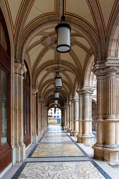 拱形走廊，柱子和悬挂的灯笼。优雅的走廊，拱顶天花板，石柱，马赛克瓷砖地板，以及复古灯笼，属于一座历史悠久的欧洲建筑。图片下载
