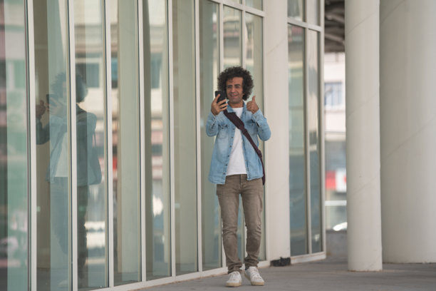 成熟男性在街上走动时使用智能手机的照片图片下载