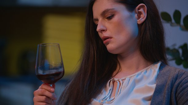 夜晚，伤心的女性独自在家中喝着一杯酒，翻看着照片册，回忆往昔，神情沉思。图片下载