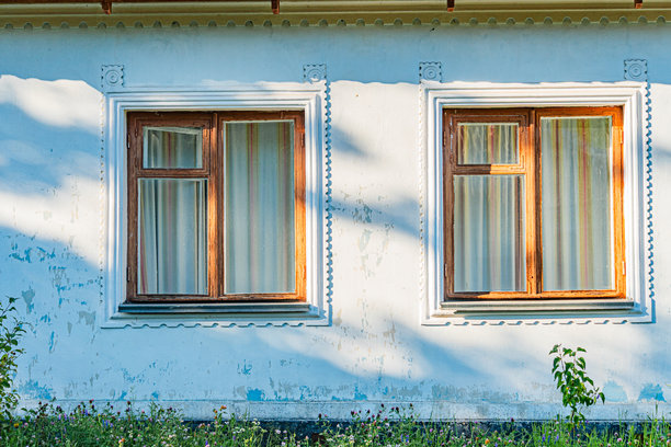 老中央欧洲建筑，带有两个窗户，一个关闭，一个半关闭，阳台栏杆可见，浅色外立面有老化迹象，白天光线，无人出现，抓拍照片。图片下载