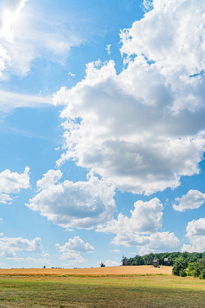 阳光明媚的古老中欧村庄 收获的田野，高大的树木，零星的云朵，开阔的乡村风景 没有人或动物可见 真实的照片，色彩自然，呈对角线构图图片下载