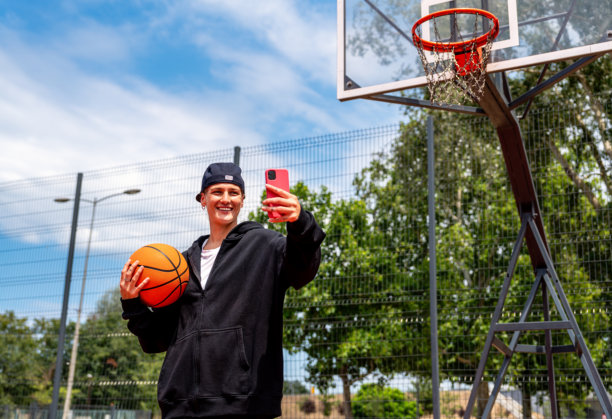 年轻城市女性在街头篮球场用智能手机发送照片信息图片下载