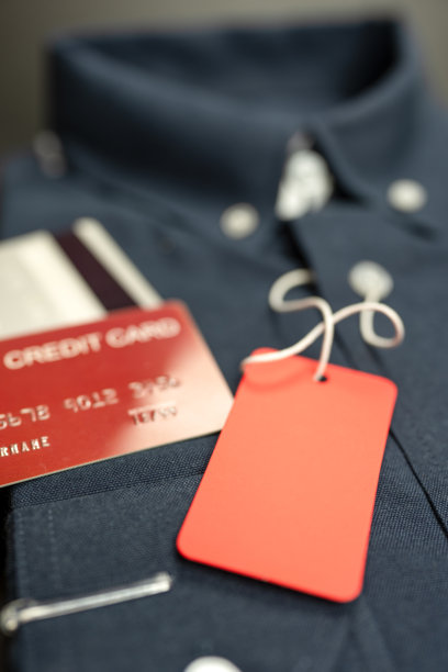 折叠的蓝色衬衫和信用卡上的红色空白标签，适用于促销和广告的照片。购物的概念。图片下载