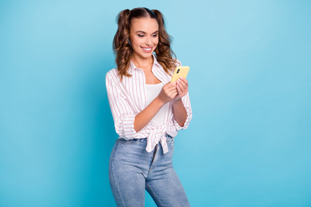 微笑着用手机阅读新闻并订阅的照片肖像，背景为鲜艳的蓝色。图片下载