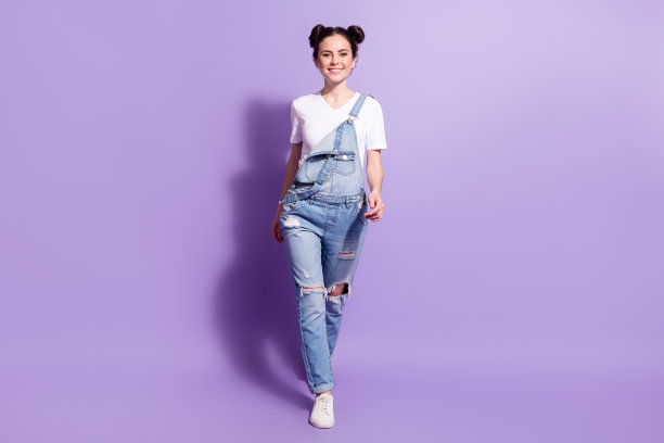 年轻漂亮女孩开心微笑，走路的全身照片，背景为紫色。图片下载