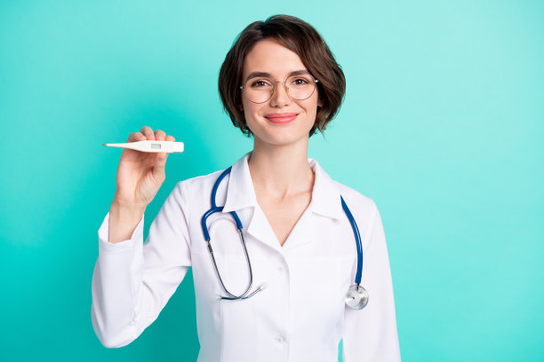 穿着白大褂的快乐女医生在鲜艳的青色背景下展示温度计的照片肖像图片下载