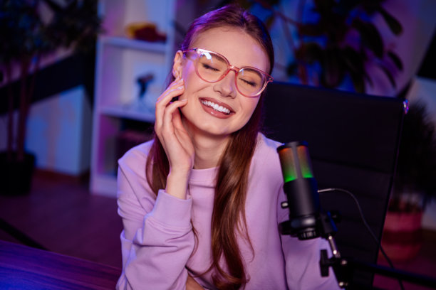 年轻女性博主在时尚的家庭工作室中使用麦克风进行在线直播，周围有五彩斑斓的霓虹灯。图片下载