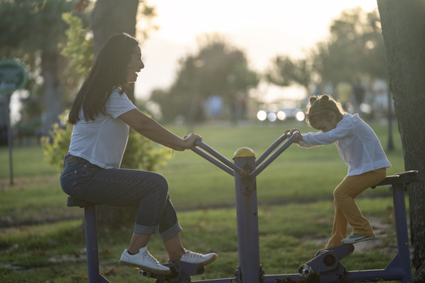 母亲和学龄前女儿在日落时分的公共健身公园锻炼的照片图片下载