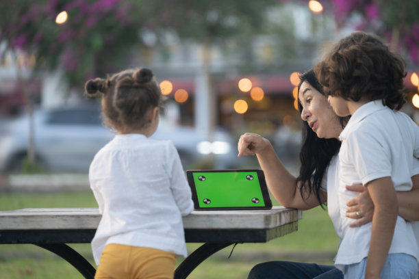 母亲、儿子和女儿在公园里使用平板电脑的照片图片下载