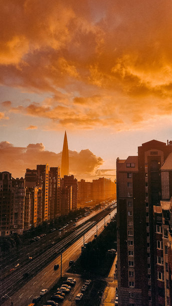 现代城市的黄昏全景，中央的摩天大楼在夏季雨中闪耀。俯瞰壮观的日落。竖版照片图片下载