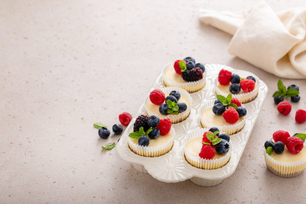 迷你芝士蛋糕，烘焙在松饼模具中，上面装饰着新鲜浆果图片下载