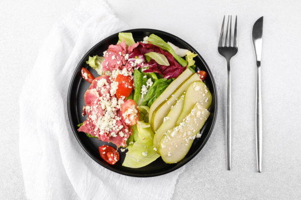 健康沙拉，搭配梨和奶酪，放在黑色碗中，背景为白色，适合清淡饮食或食谱内容图片下载