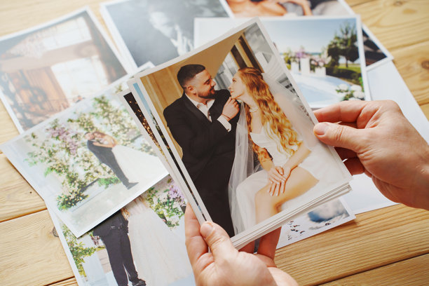 男人的手放在木桌上，展示婚礼照片。图片下载