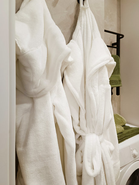 酒店浴室内悬挂的白色毛巾浴袍。特写，竖版照片。图片下载