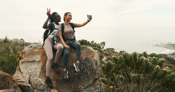 女孩、朋友们在山上徒步旅行时自拍，兴奋而快乐，做出和平手势，享受大自然。女性们开心地拍照作为个人资料照片，夏季冒险的徒步旅行或社交网络分享。图片下载