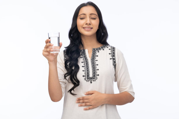 微笑的女性手持一杯水的肖像照片，背景为白色。图片下载