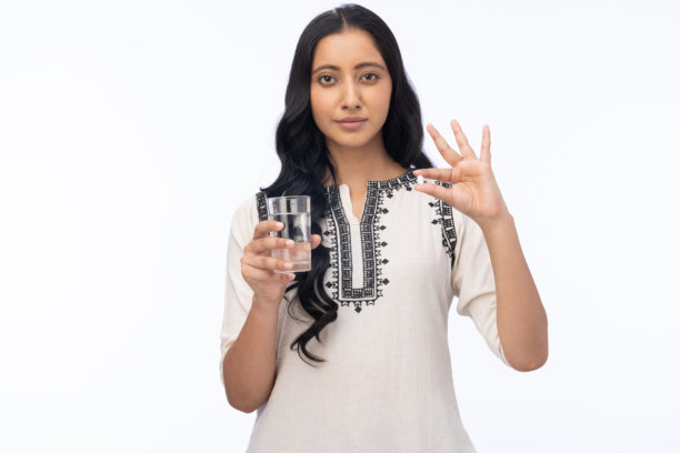 微笑的女性手持一杯水的肖像照片，背景为白色。图片下载