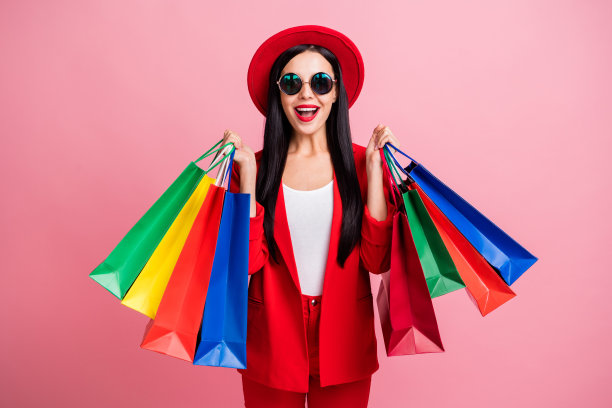 兴奋女孩手持购物袋的照片肖像，背景为柔和的粉色。图片下载