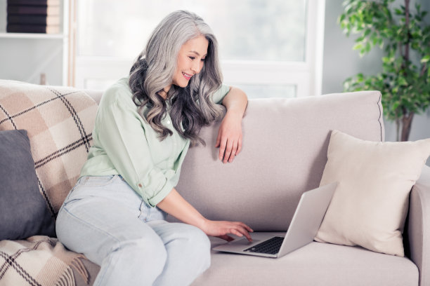老年女性在家中沙发上使用笔记本电脑浏览互联网的照片肖像图片下载