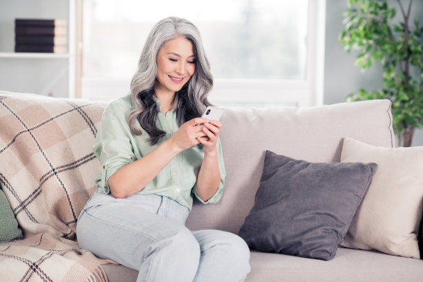 老年女性在家中沙发上使用手机的肖像照片图片下载