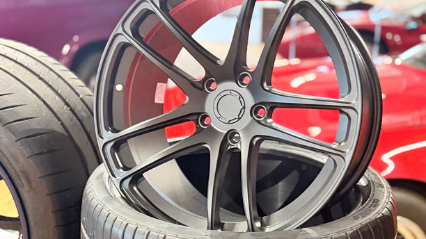 车轮铝合金轮毂与轮胎，车间前视特写，多辐条轮圈与中央轮毂，产品照片，浅景深和模糊背景图片下载