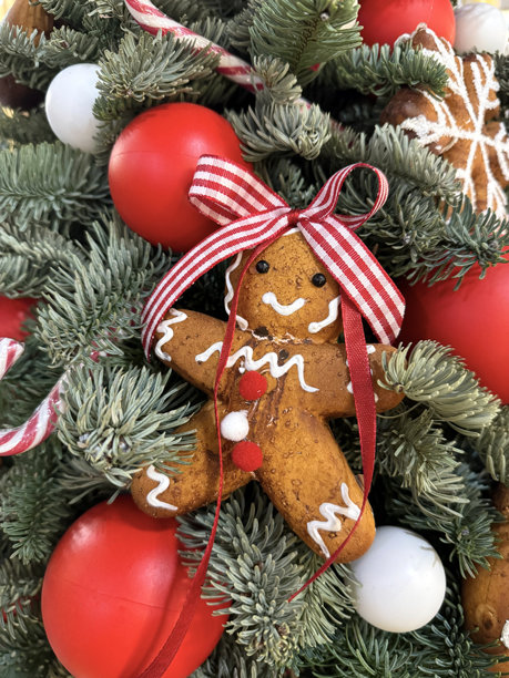 垂直照片展示了挂在圣诞树上的姜饼人装饰和红色球体的特写，营造出节日和温馨的假日氛围，为新年做准备。图片下载