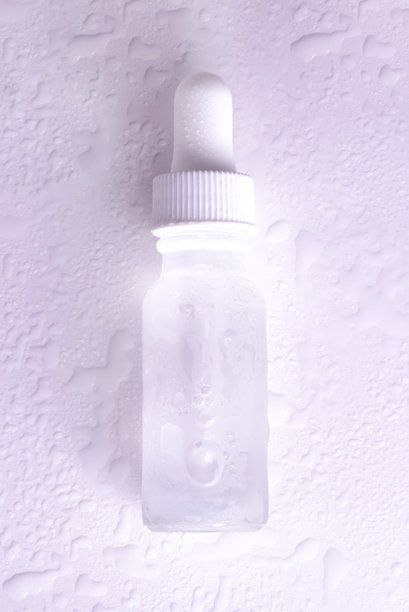 带水珠的玻璃精华瓶，湿润背景，清洁护肤和保湿概念，9:16真实照片。图片下载