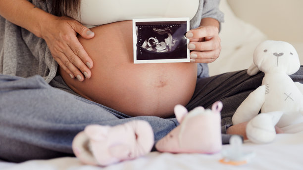 孕妇展示超声波照片 - 床上特写肚子图片下载