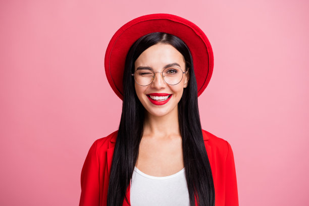 戴眼镜的女孩在粉色背景前眨眼的照片肖像图片下载