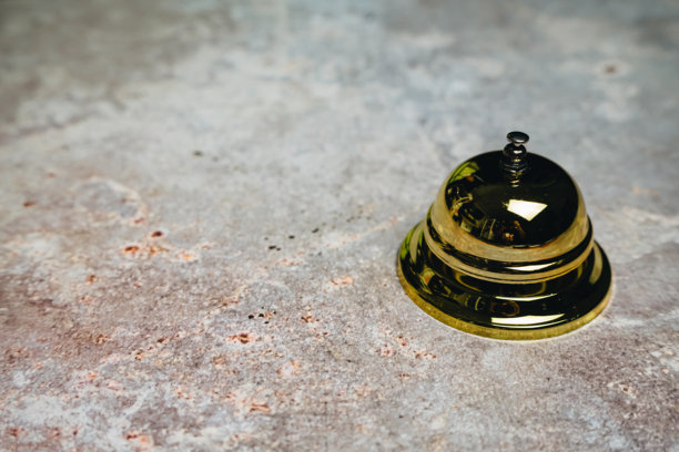 优雅的金色服务铃放置在有纹理的表面上，适用于酒店、接待或客户服务主题的库存照片图片下载