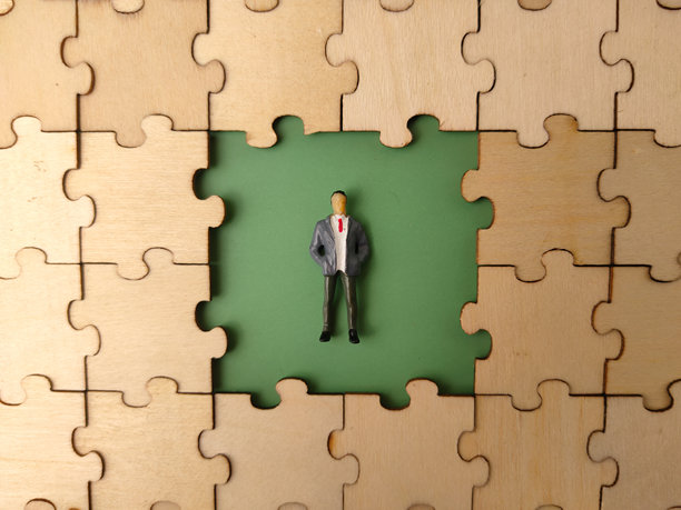 这张图片描绘了一个微型人物站在一个木制拼图的框架内，而拼图的中央部分缺失。图片下载