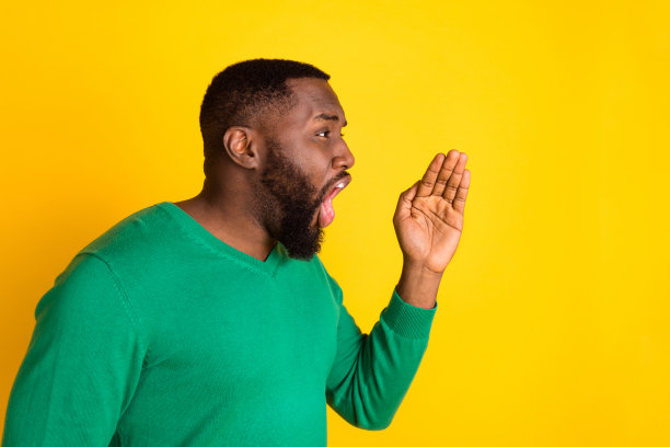 侧面肖像照片，男人在明亮的黄色背景下大声喊叫，传递新闻信息，留有空白空间。图片下载