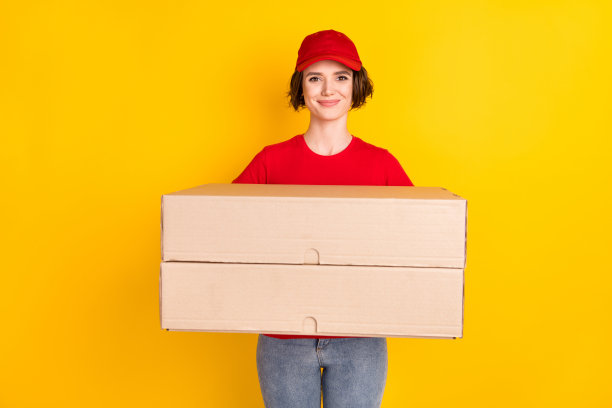 女性工作人员在鲜艳的黄色背景下保持两个大箱子的移动服务的照片肖像图片下载
