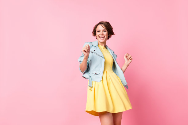 乐观的棕发女士穿着夹克裙子在粉色背景上跳舞的照片图片下载