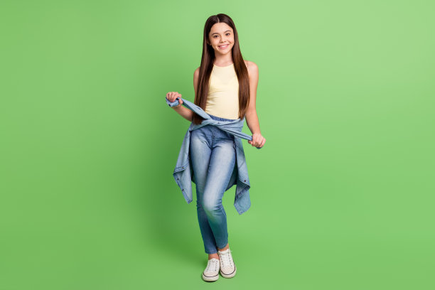 年轻漂亮可爱的微笑女孩在绿色背景上摆姿势的全身照片图片下载