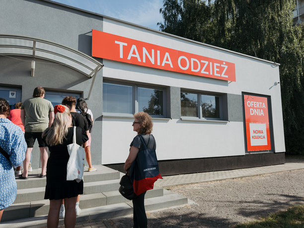 2025年8月23日，波兰佐里。人们在二手服装店外排队，店面上挂着“Tania Odzież”的招牌，零售和消费行为的编辑照片。图片下载