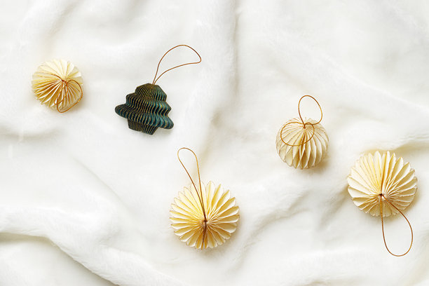 白色毛绒背景上的纸质新年装饰品平铺，米色球和绿色圣诞树，冬季节日庆祝静物。极简照片，优雅的节日装饰，俯视图，留白空间。图片下载