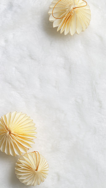 平铺的纸质新年装饰品，金色米色圣诞球放在白色毛皮背景上，冬季节日静物。简约照片，优雅的节日装饰，俯视图，留白，手机格式。图片下载