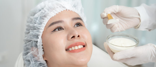 美丽女性在水疗中心进行面部护理。健康女性的面部涂抹护肤霜。护肤霜广告，抗皱、婴儿般的肌肤、美白、保湿、收缩毛孔精华、年轻化。图片下载