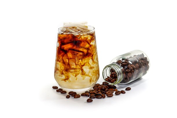 冰美式椰子咖啡的图片，背景为白色，咖啡豆散落在瓶子周围，突出孤立的概念。图片下载