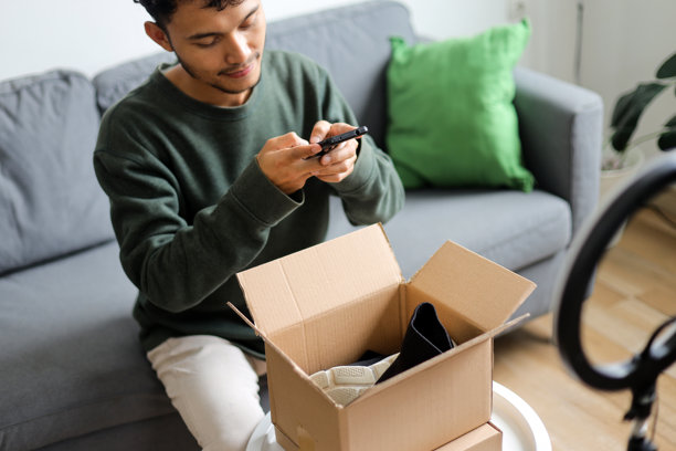年轻内容创作者在开箱盒内用智能手机拍摄产品照片，准备进行评测图片下载