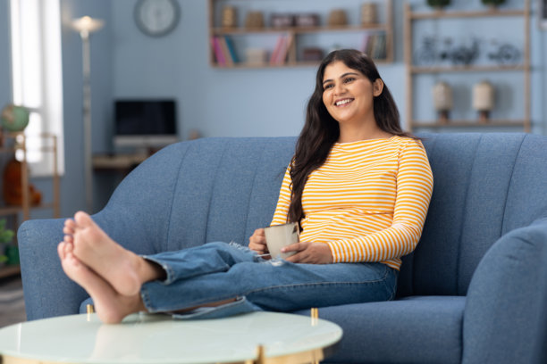 年轻女性在家中沙发上喝咖啡的照片图片下载