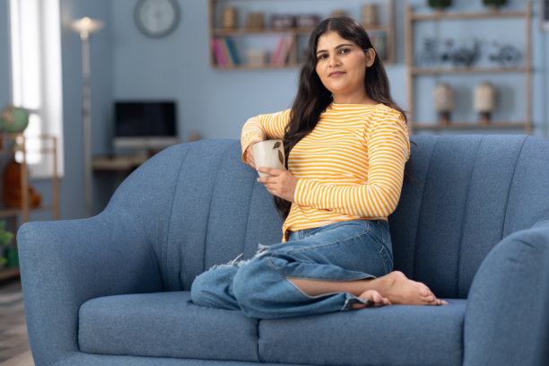 年轻女性在家中沙发上喝咖啡的照片图片下载