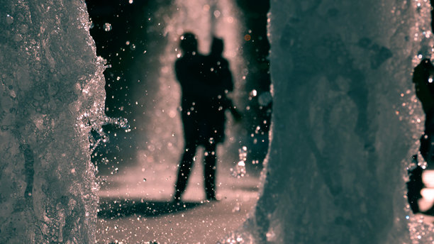 逆光下模糊人影的喷泉照片图片下载