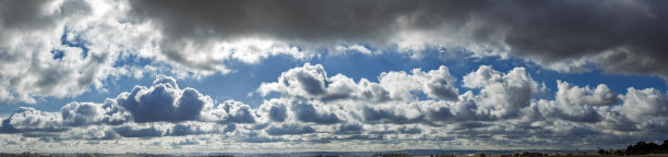 戏剧性的高对比度云层全景照片，阳光透过云层洒下，太阳隐藏在云后。图片下载