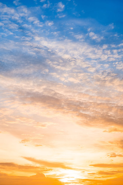 美丽奢华的柔和渐变橙金色云彩和阳光映衬在蓝天上，适合用作背景，拍摄于傍晚黄昏，超大尺寸，高分辨率风景照片，竖版。图片下载