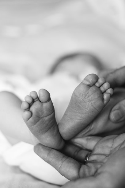 新生儿的小脚丫在母亲的怀抱中。黑白照片。母性概念图像。特写新生儿的脚趾、脚跟和脚。图片下载