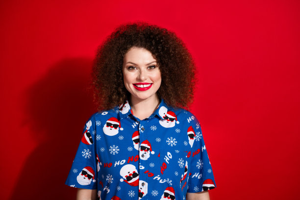 可爱的年轻女士的照片肖像，露出灿烂的笑容，穿着时尚的蓝色印花圣诞服装，背景为红色。图片下载